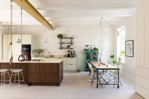 Open keuken en eetkamer met houten kookeiland, okergele balk en turquoise vintage kast