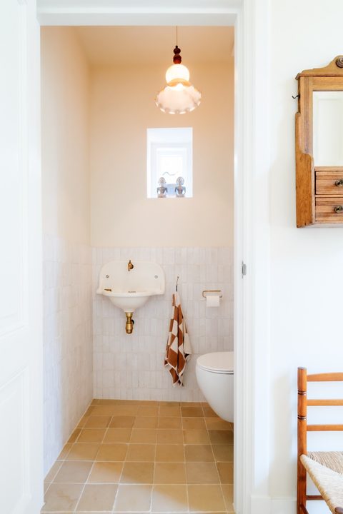 Klein toilet met beige zelliges en een vintage wastafel